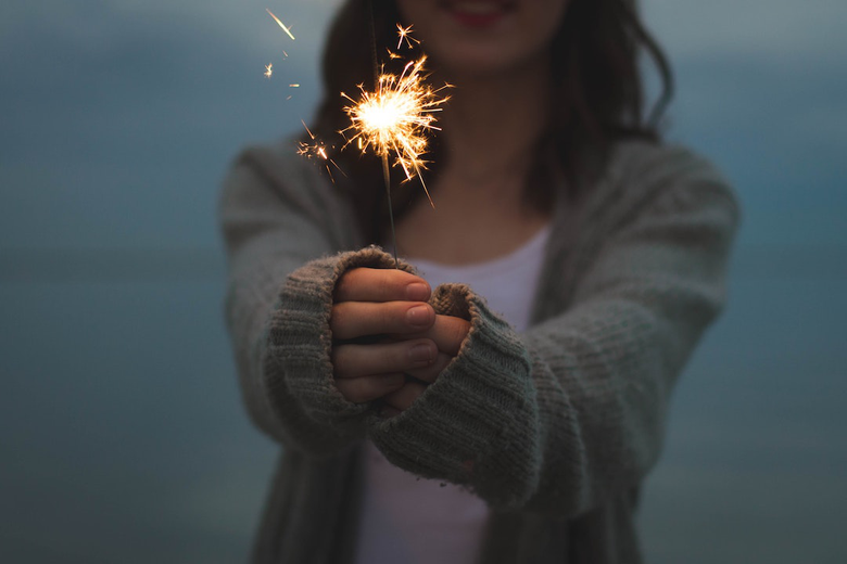Woman holding a sparkler out in front of her